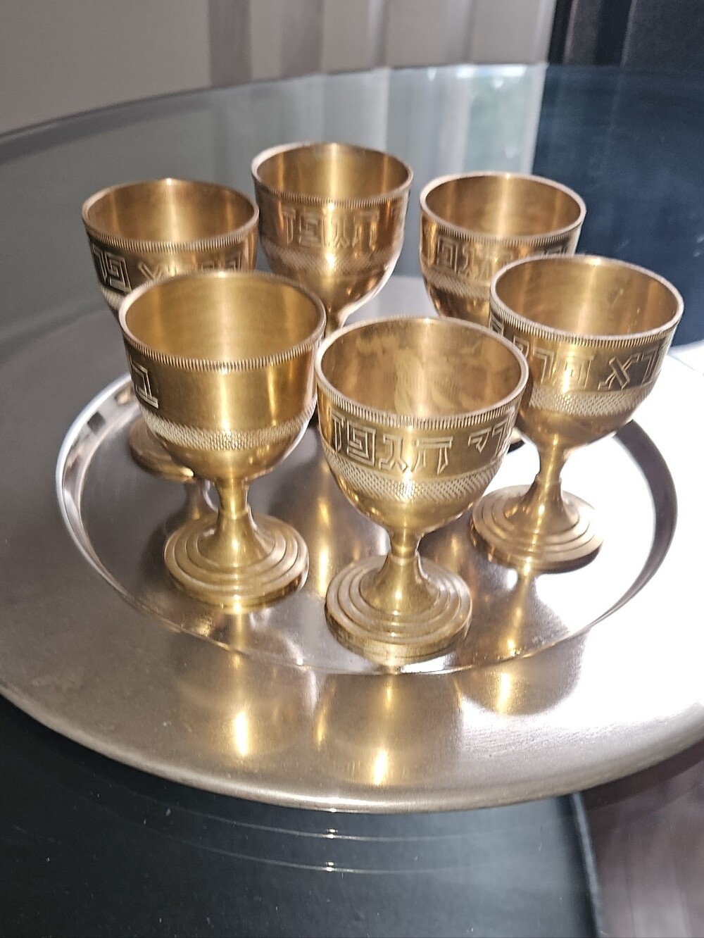 Brass kiddush cup set includes six small goblets and a matching circular tray.